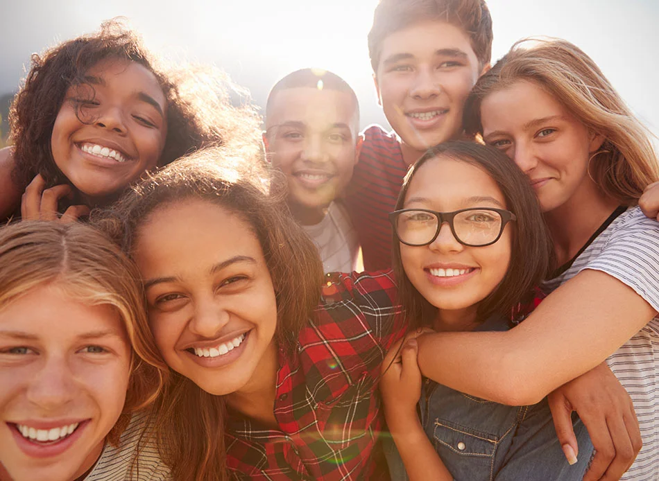 A group of teens smiling with the sun behind them - Teen Dental Care in Fort Lee, NJ