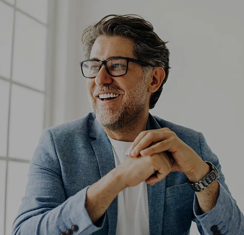 Middle-aged man with salt and pepper hair and black glasses smiling off to the side - north jersey dental group