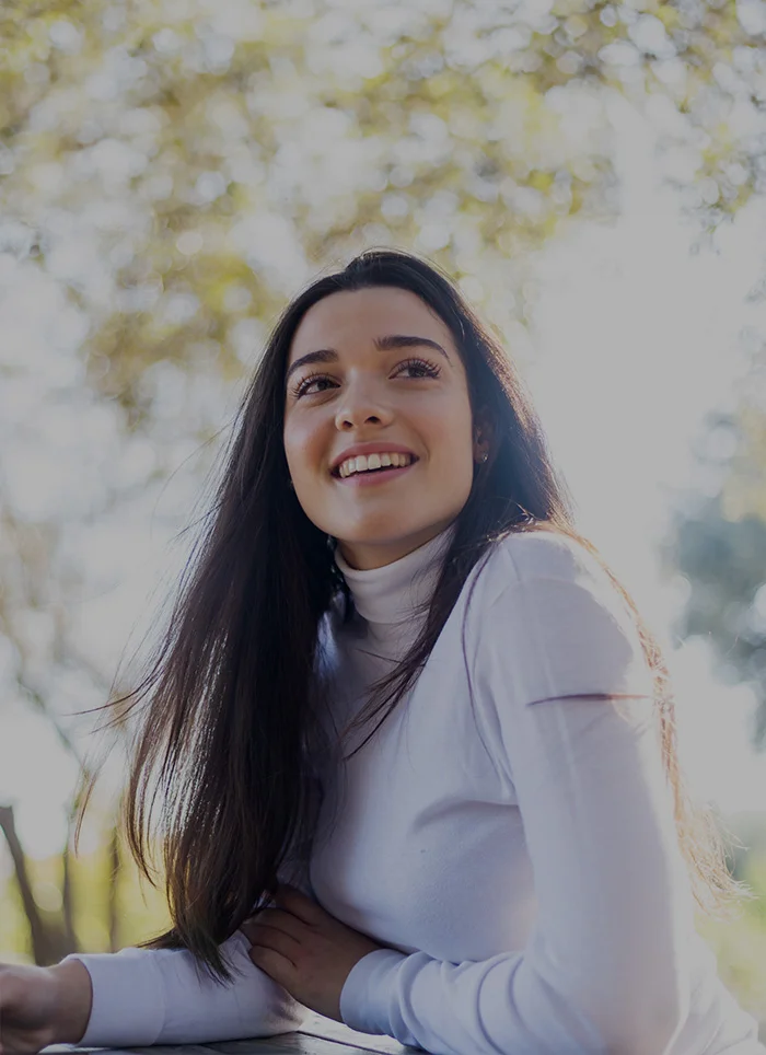 teenage girl with long brown hair smiling outside - North Jersey Dental Group